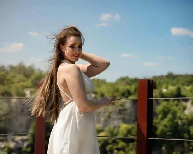 Woman in a white dress, hair in the wind, rocks and sky