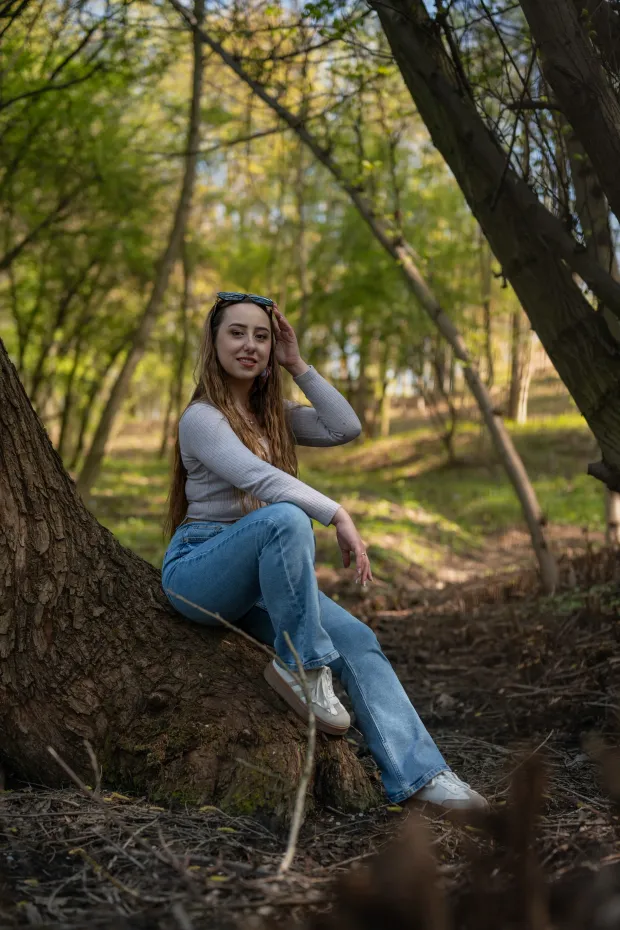 Woman in jeans on a tree trunk in the forest