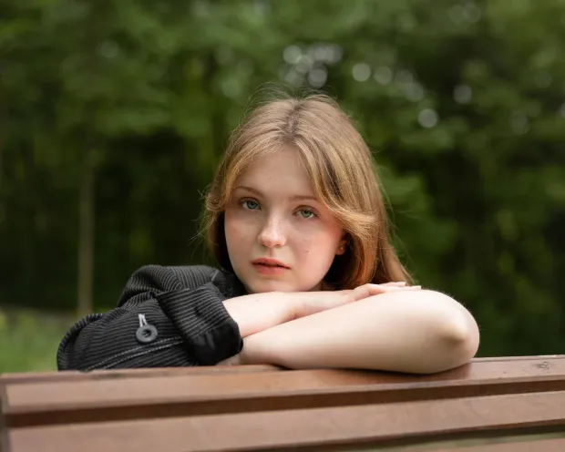 Portrait of a freckled girl on a park bench